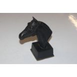 A bronze bust of a horses head, raised on square s