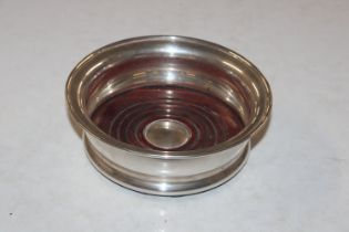 A turned wooden and silver mounted bottle coaster