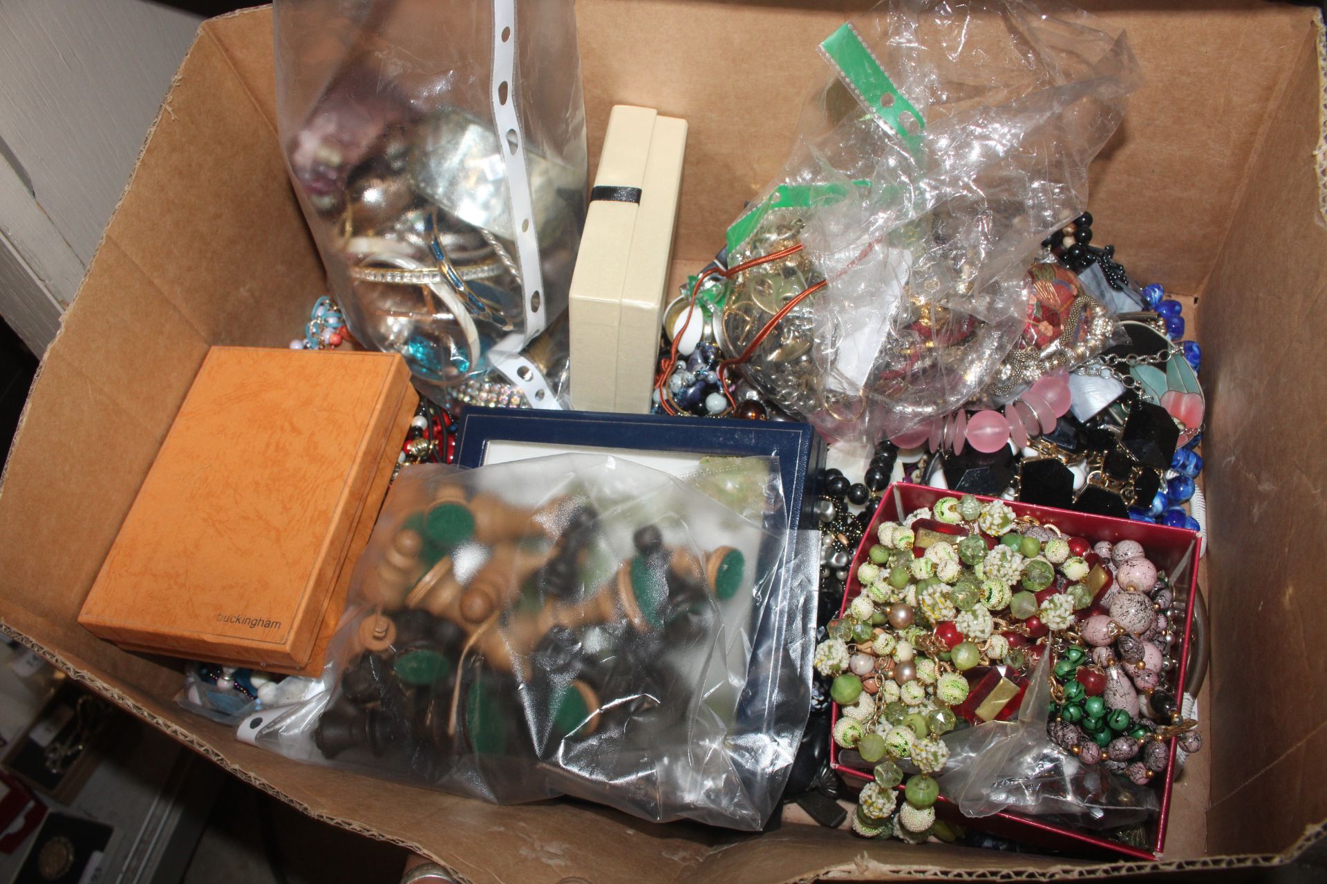 A box containing chess pieces; various costume jew