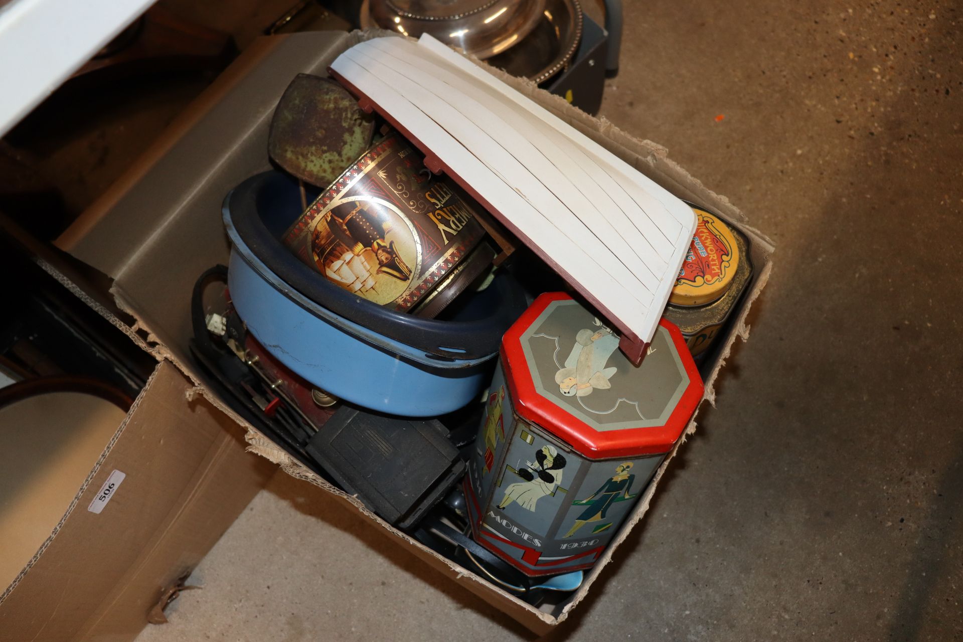 A box containing various tins, model boat etc.