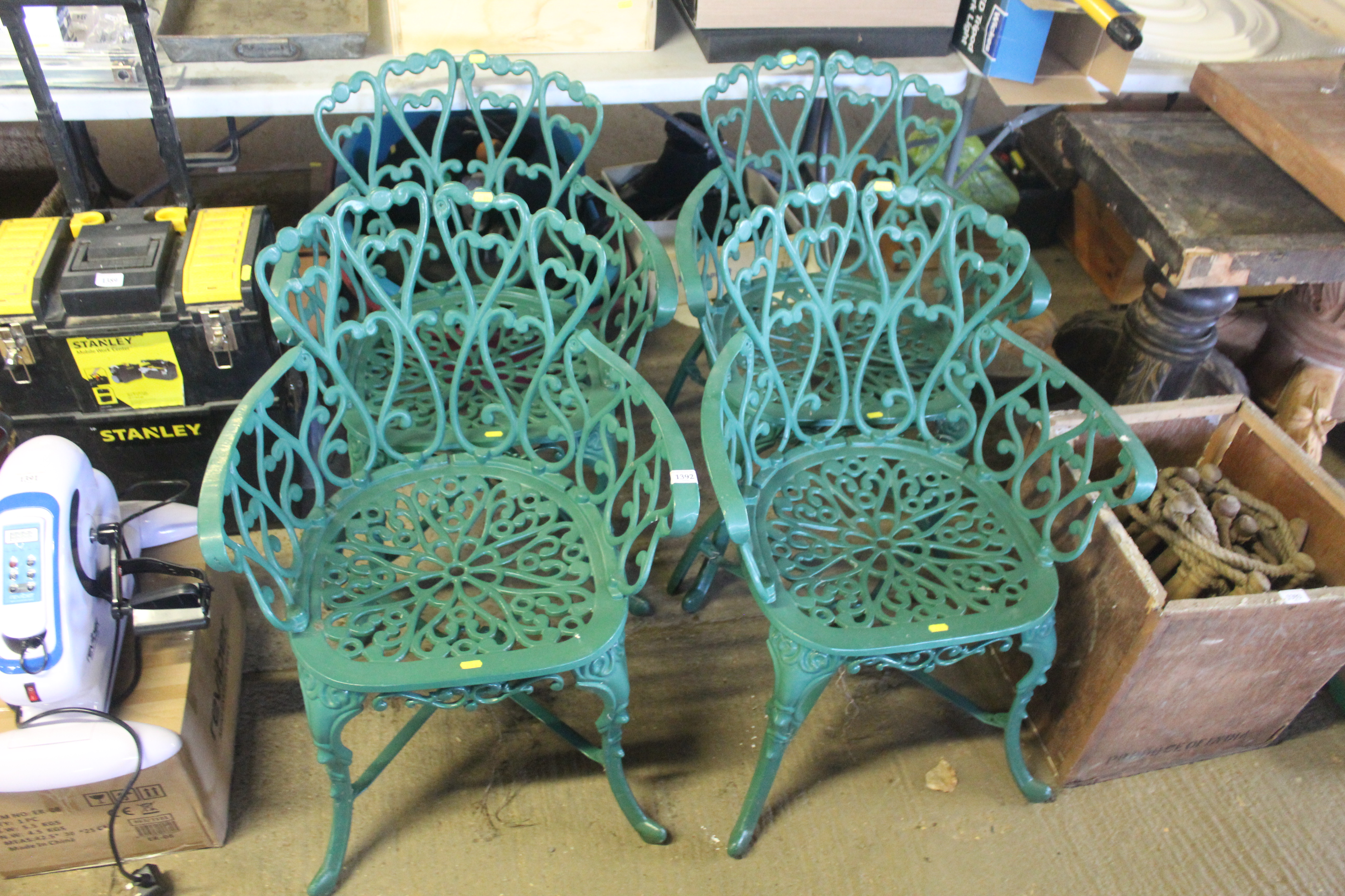 A set of four ornate green painted metal garden ar