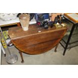 An oak drop leaf table raised on pad foot supports