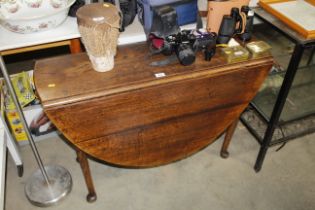 An oak drop leaf table raised on pad foot supports