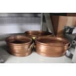 A graduated set of three copper and brass twin han