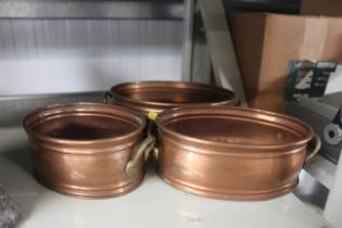 A graduated set of three copper and brass twin han