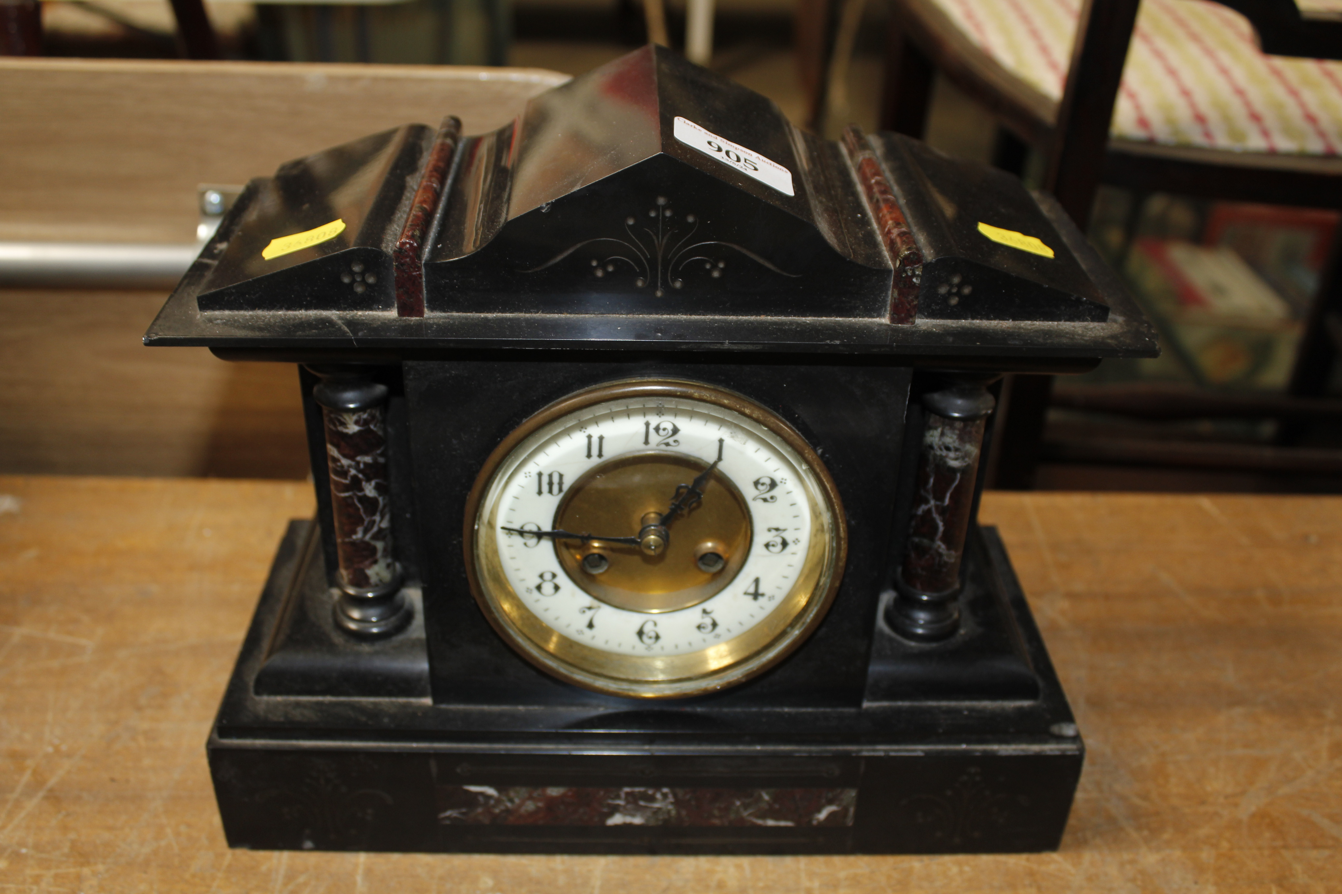 A late Victorian black slate two hole mantel clock