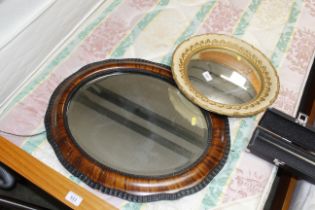 An oval framed bevelled edge wall mirror and a cir