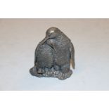 A filled silver ornament, two penguins
