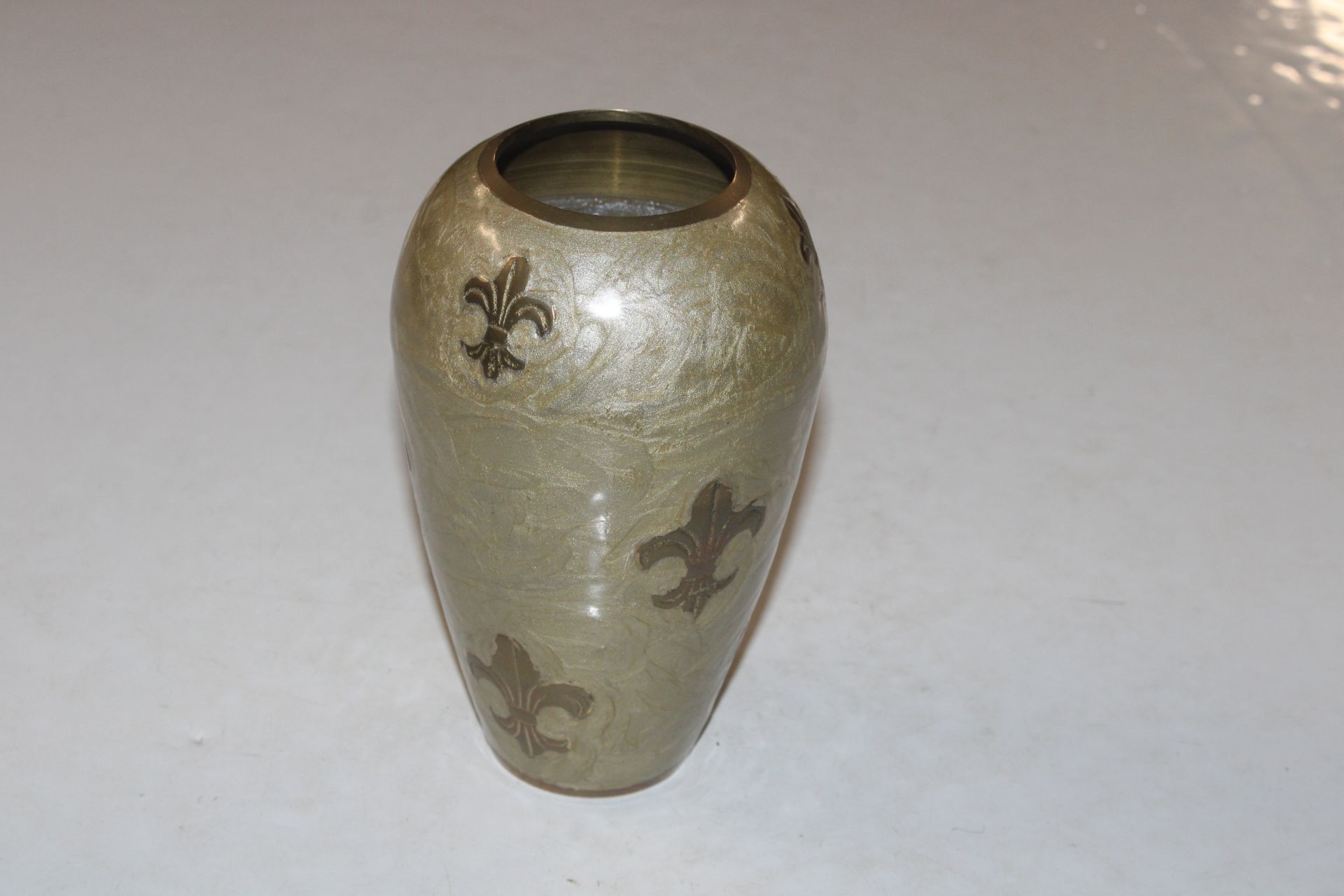 A brass vase with Fleur de Lys decoration