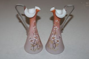 A pair of satin glass floral decorated ewers