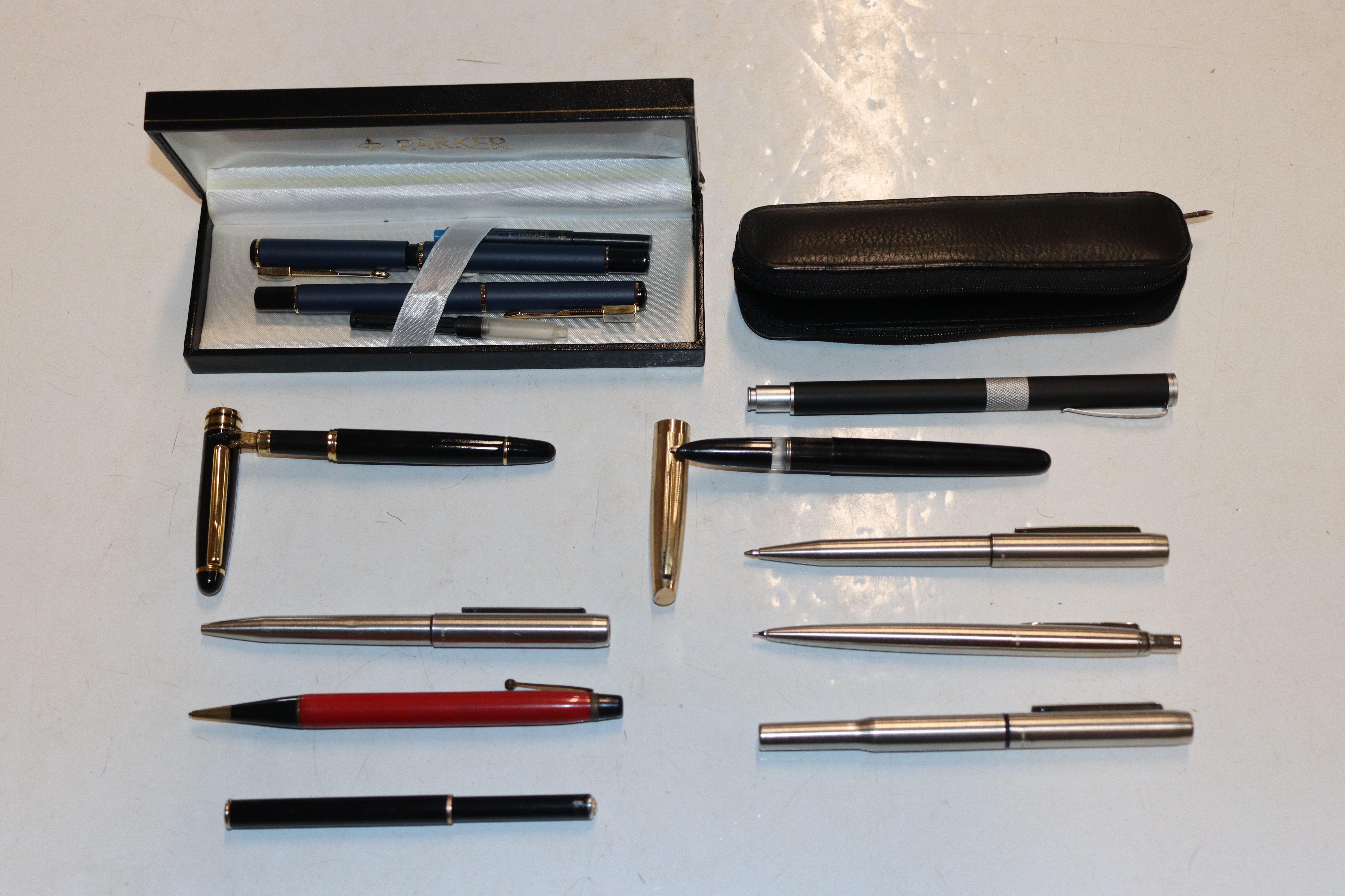 A tin containing Parker fountain pens and others