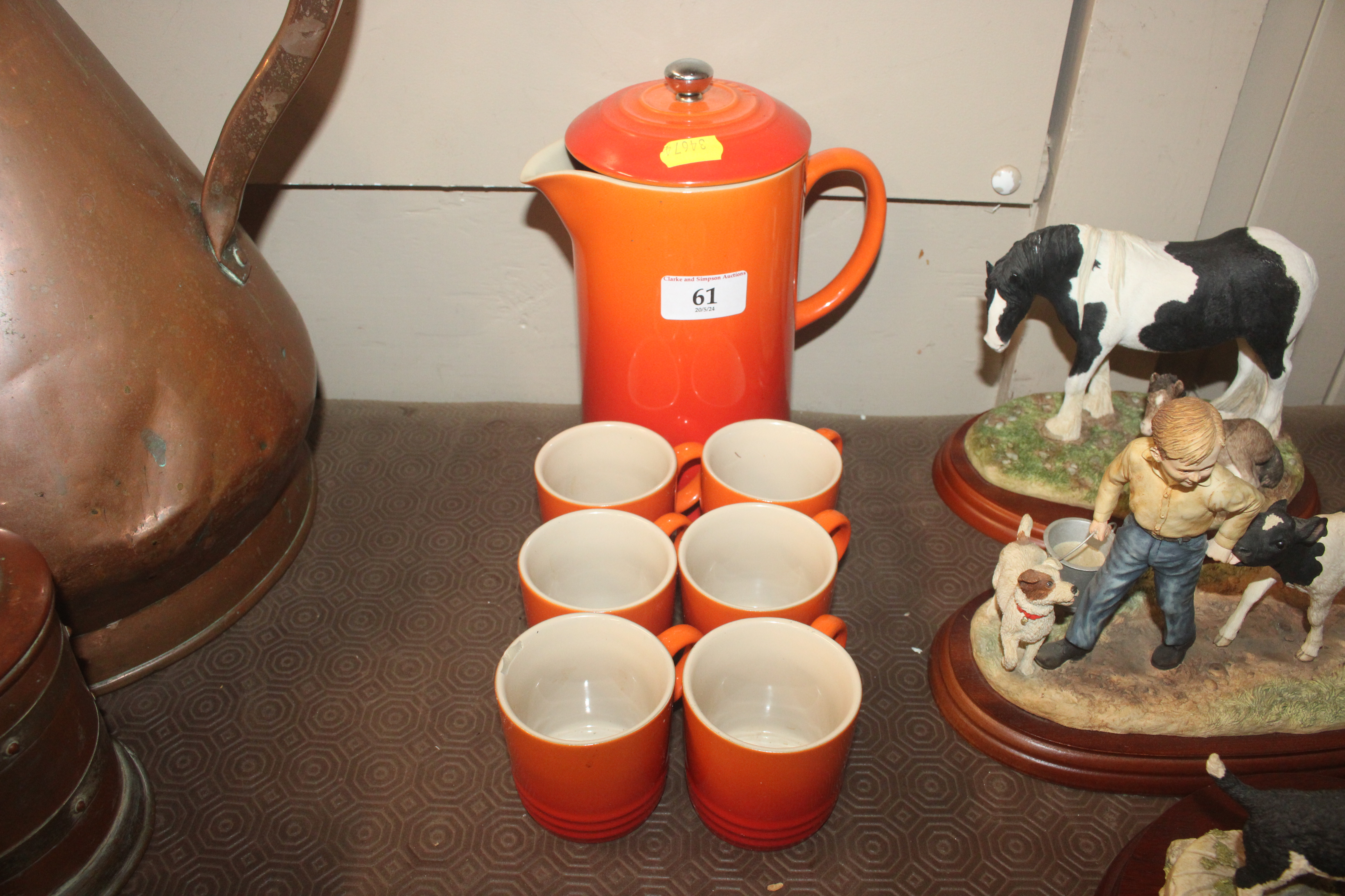 A Le Creuset orange coffee pot and six cups