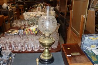 A brass oil lamp with glass shade and chimney