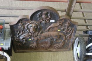 A large cast iron painted fire back with lion moti