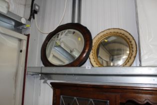 An oval framed bevel edged wall mirror and a circu