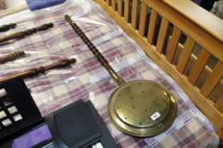 A brass warming pan with turned wooden handle