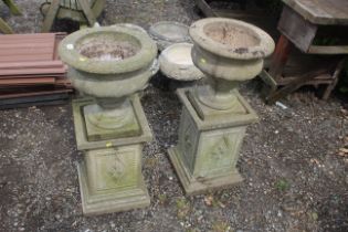 A pair of concrete garden urns raised on concrete