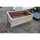 A wooden bordered plant trough raised on legs