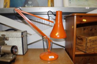 An orange Angle Poise type lamp