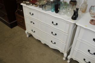 A white painted three drawer serpentine fronted chest