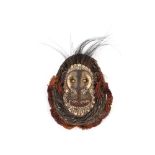 An Ethnic face mask with painted seashell and bone decoration to the face, within a wicker and straw