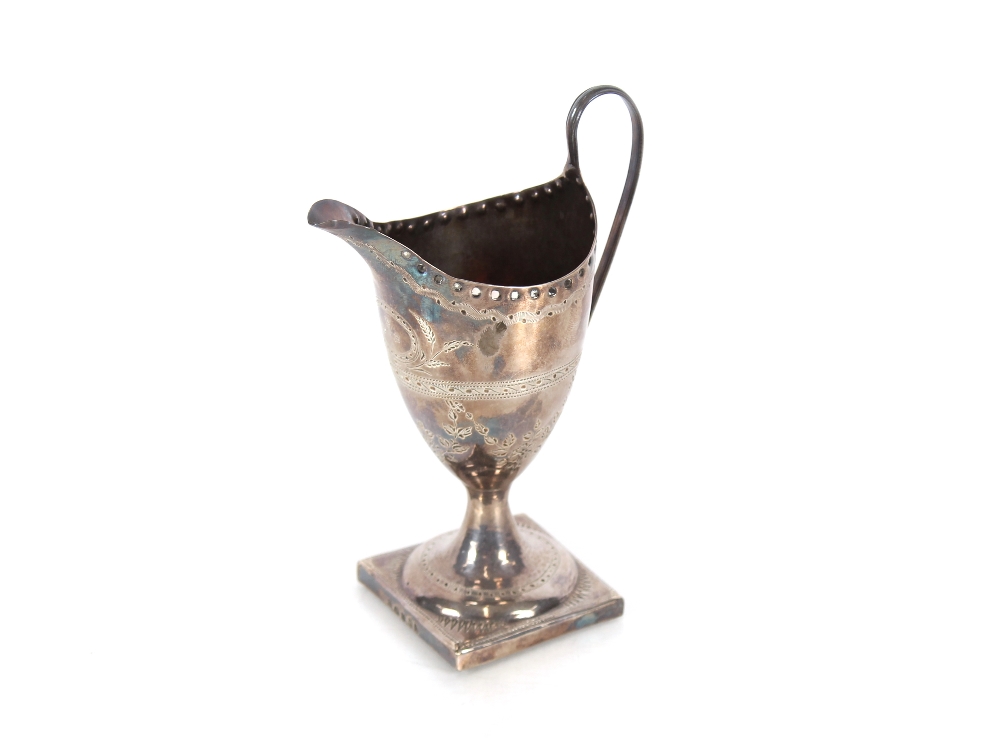 A George III silver pedestal cream jug, having foliate scroll decoration the central cartouche