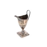 A George III silver pedestal cream jug, having foliate scroll decoration the central cartouche
