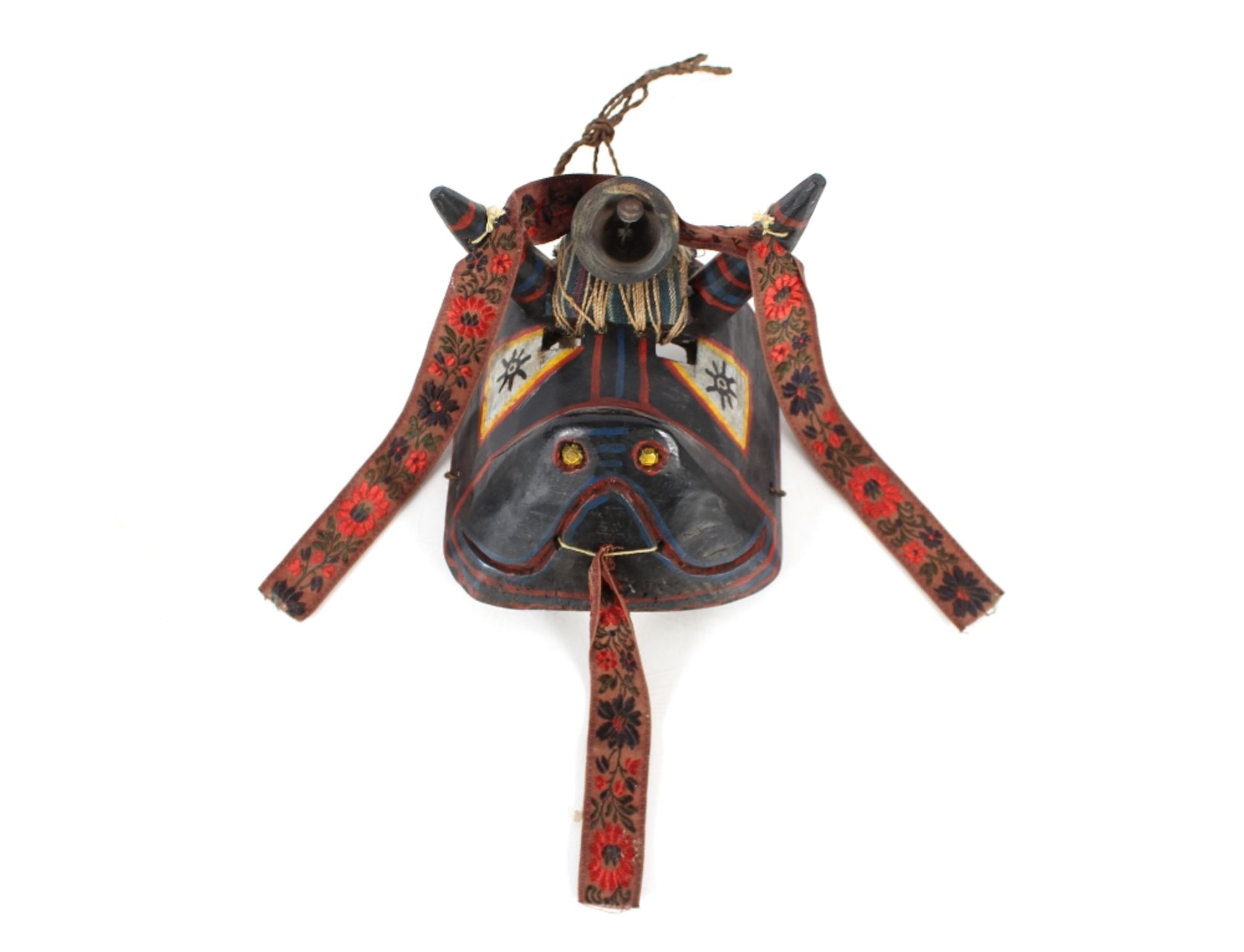 A brightly coloured Ethnic face mask, having horns supporting a central bell with brightly