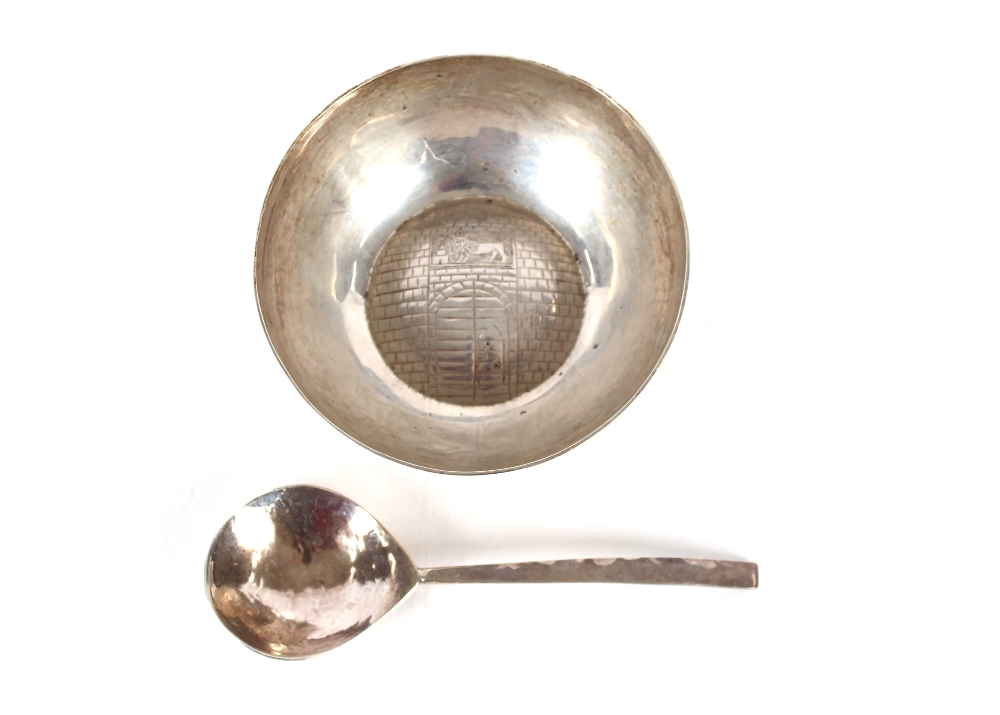 A modern silver hand forged caddy spoon; and a small circular white metal bowl unmarked with naïve