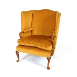 A Georgian style wing back easy chair, upholstered in old gold Dralon, having scrolled arms and