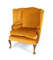 A Georgian style wing back easy chair, upholstered in old gold Dralon, having scrolled arms and