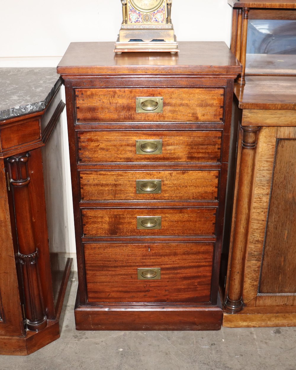 A mahogany chest of narrow proportions fitted five graduated drawers, with sunken brass military