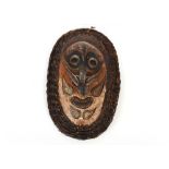 A large oval shield shape Ethnic face mask, having painted decoration and wicker work borders, 60cm