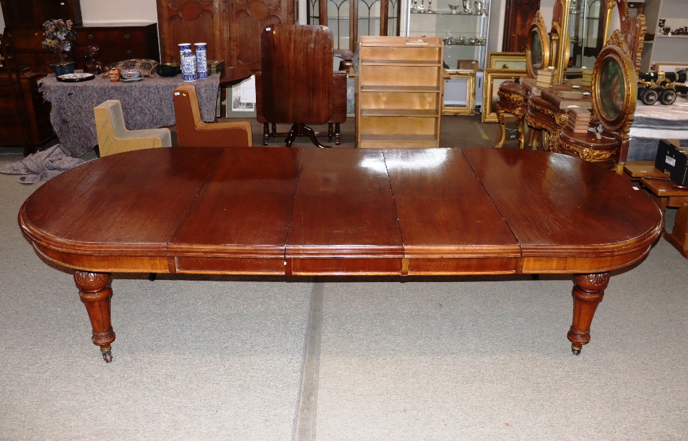 A large Victorian mahogany extending dining table with three extra leaves, raised on leaf carved and