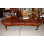 A large Victorian mahogany extending dining table with three extra leaves, raised on leaf carved and