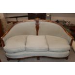 An early 20th Century carved walnut salon suite, comprising curved three seater settee with