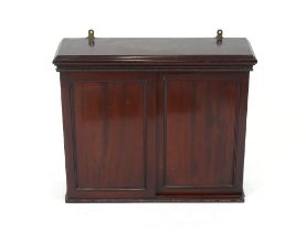 An Edwardian mahogany wall cupboard the interior adjustable shelf enclosed by a pair of sliding