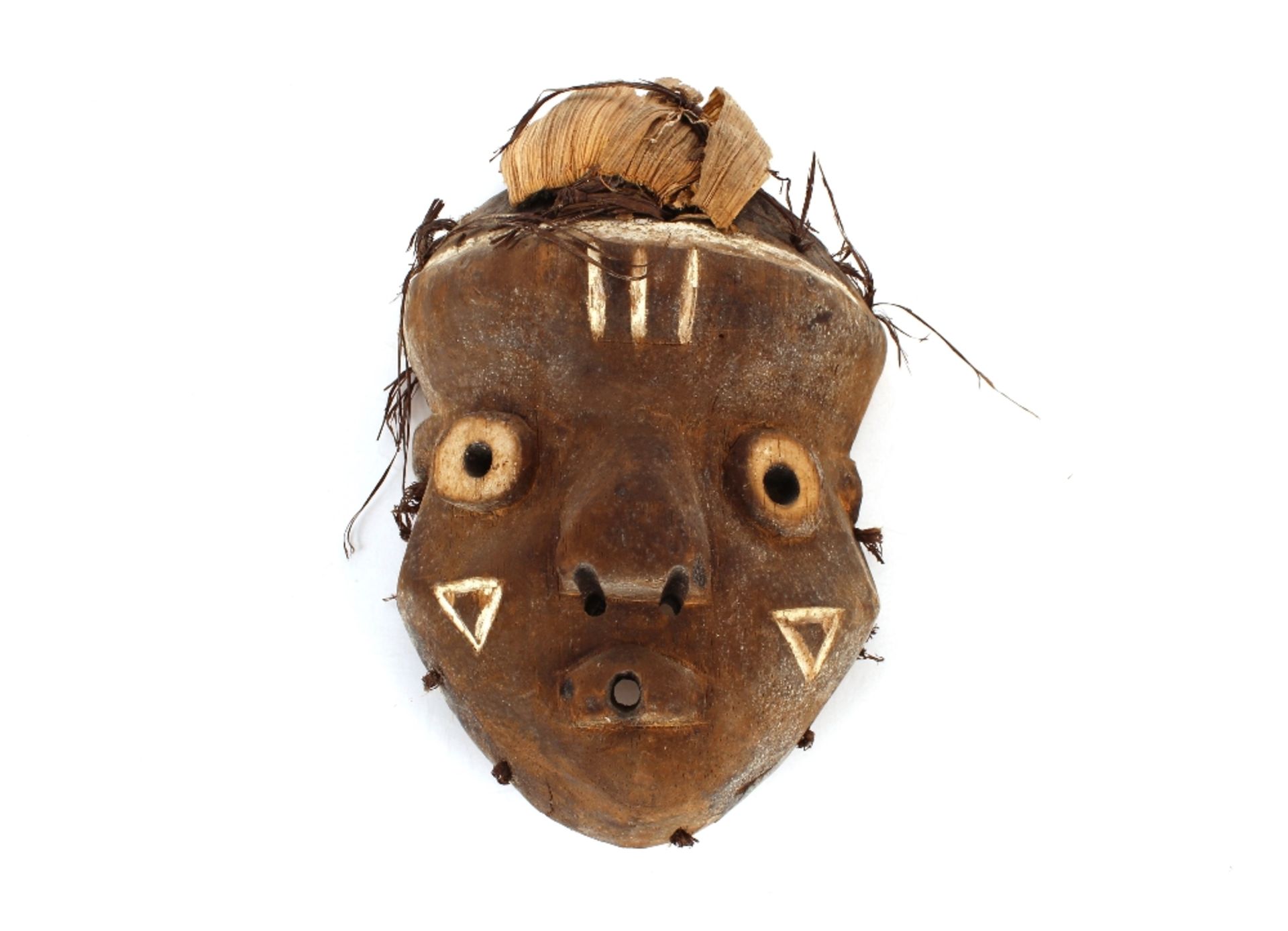 A soft wood carved and painted Ethnic tribal face mask with husk decoration, 29cm