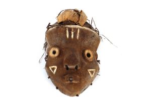 A soft wood carved and painted Ethnic tribal face mask with husk decoration, 29cm