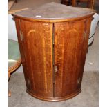 A 19th Century oak and mahogany cross banded elliptical hanging corner cupboard, the shaped interior