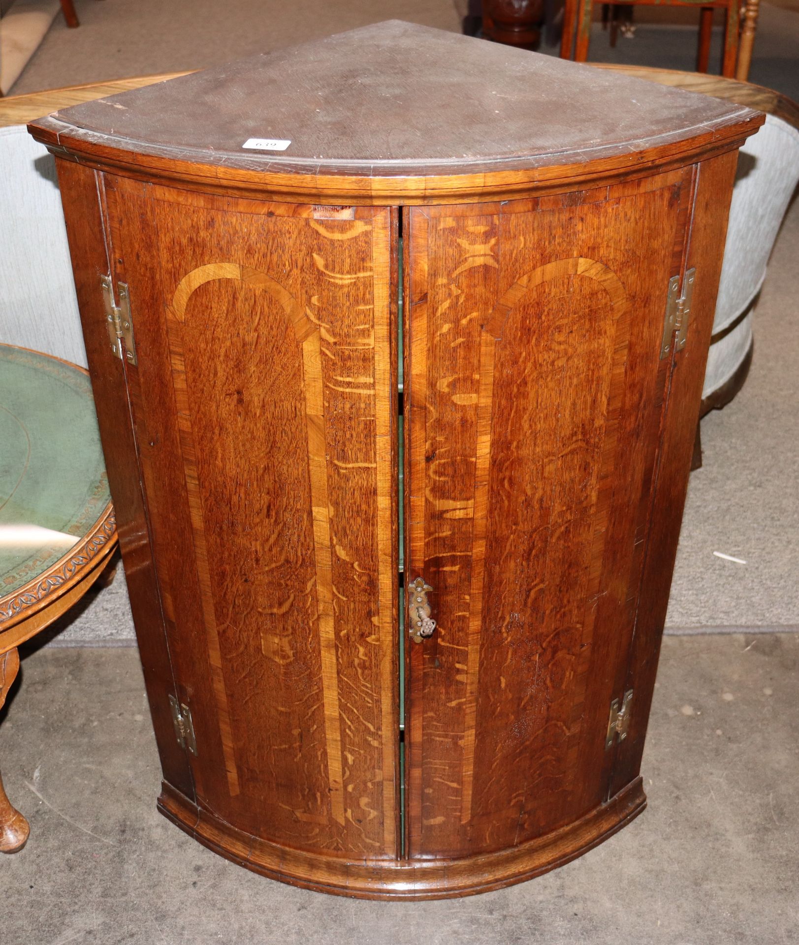 A 19th Century oak and mahogany cross banded elliptical hanging corner cupboard, the shaped interior