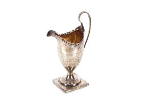 A George III silver pedestal cream jug, having naïve foliate engraved decoration, spread foot set to