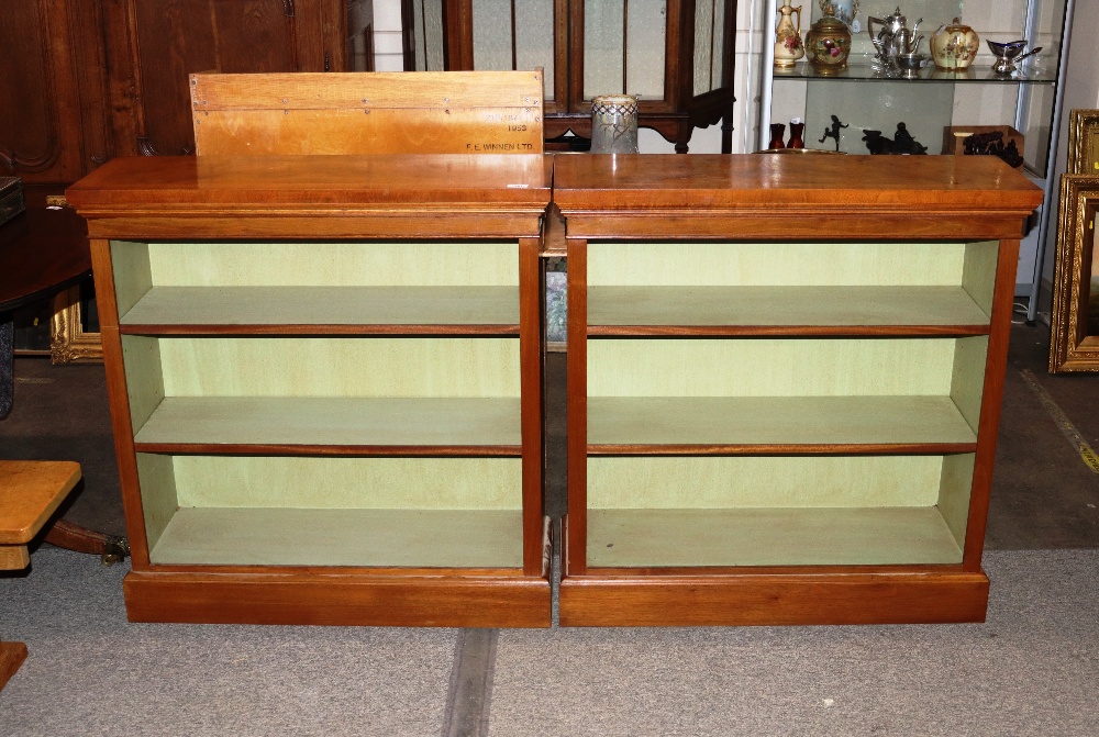 A pair of walnut open fronted bookcases, fitted adjustable shelves raised on platform plinth