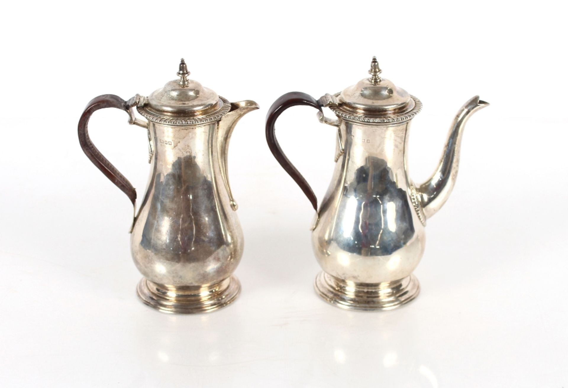 A George V silver Café au Lait set of baluster form, the domed hinged lids surmounted by acorn