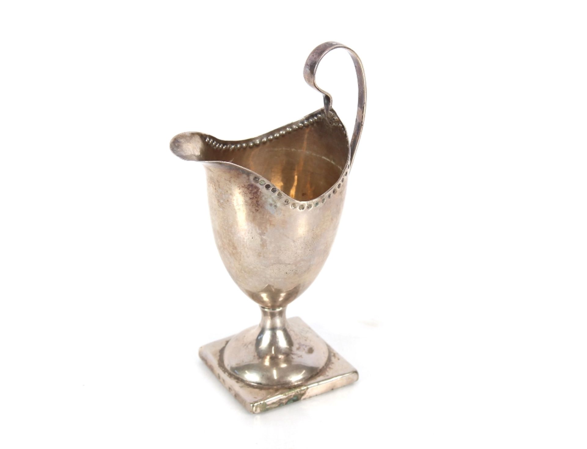 A Georgian silver pedestal cream jug, of plain form with looped handle, spread foot and square base,