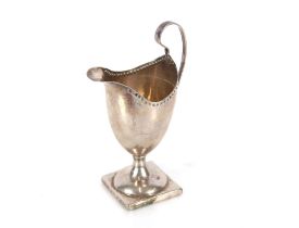 A Georgian silver pedestal cream jug, of plain form with looped handle, spread foot and square base,