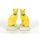 A pair of Staffordshire yellow glazed figures of seated cats on cushions, 20cm high