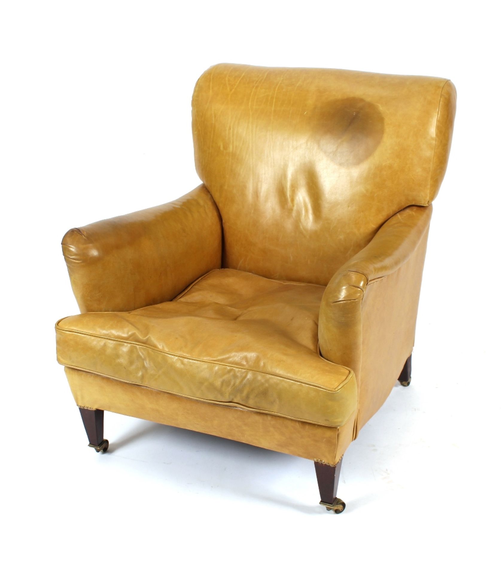 An early 20th Century tan leather covered deep seated armchair, raised on square tapering supports