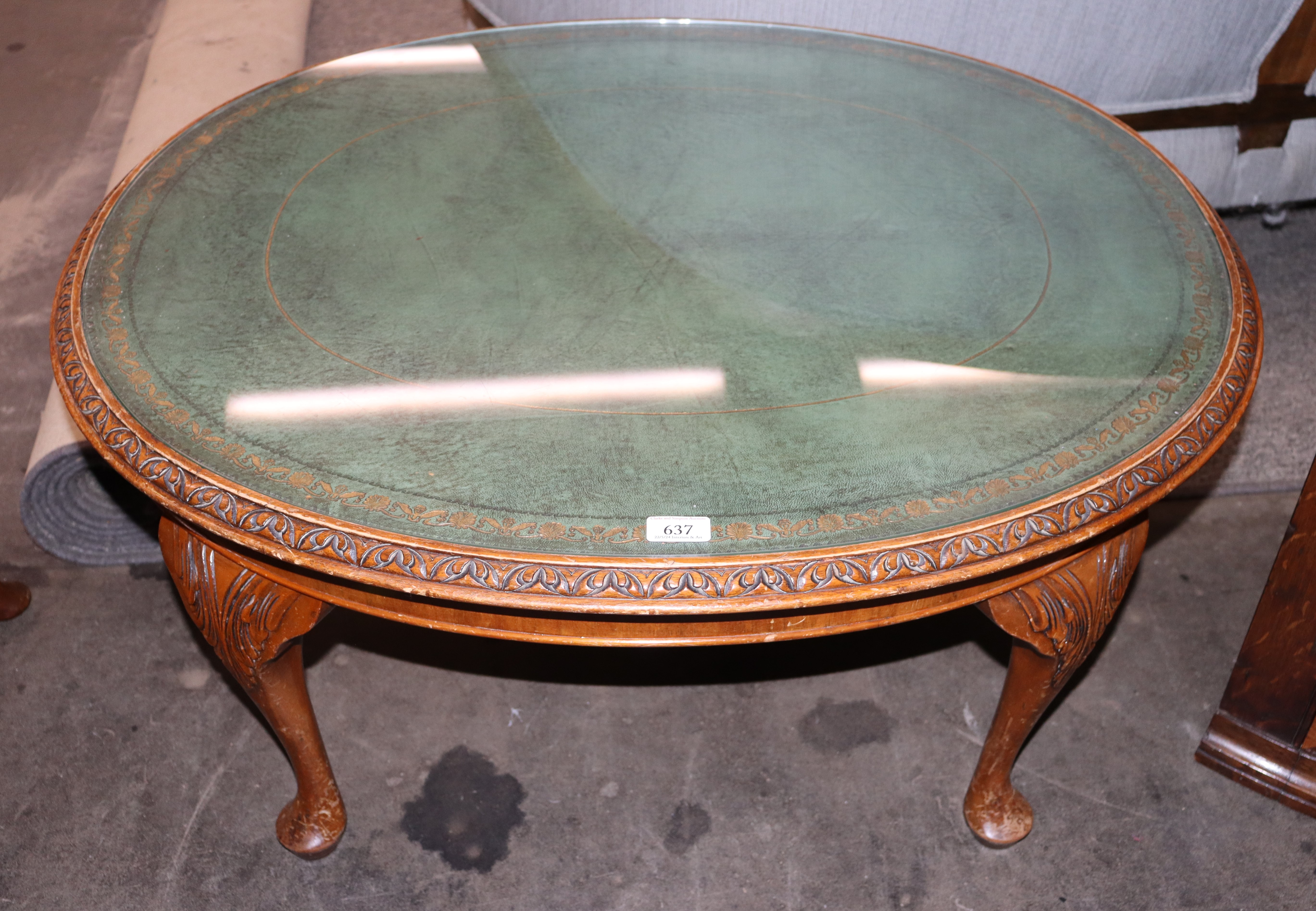 A reproduction mahogany oval coffee table with leather inset top, raised on carved cabriole