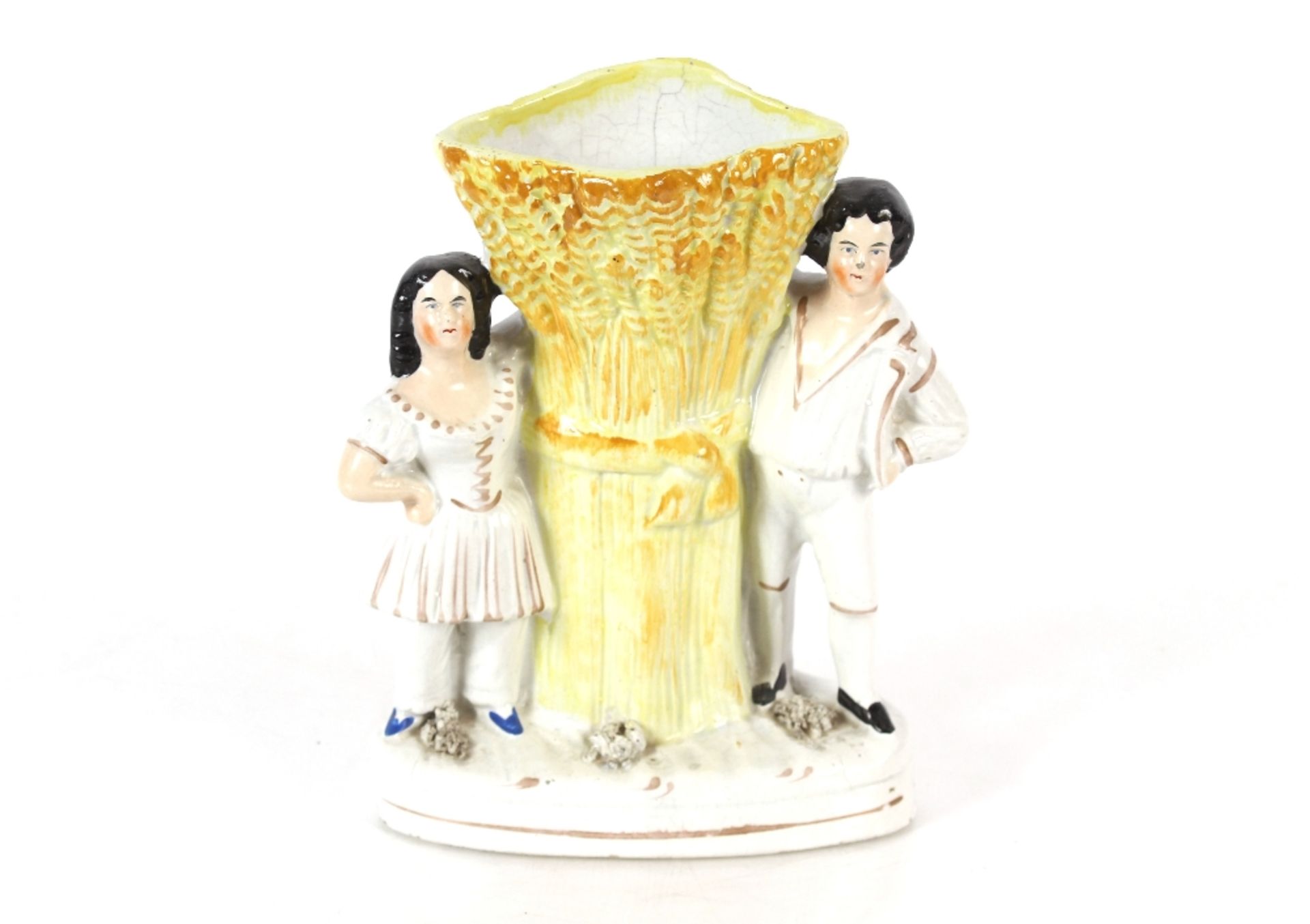 A Staffordshire spill holder in the form of a maid and youth beside a stoop of corn, 17cm high;